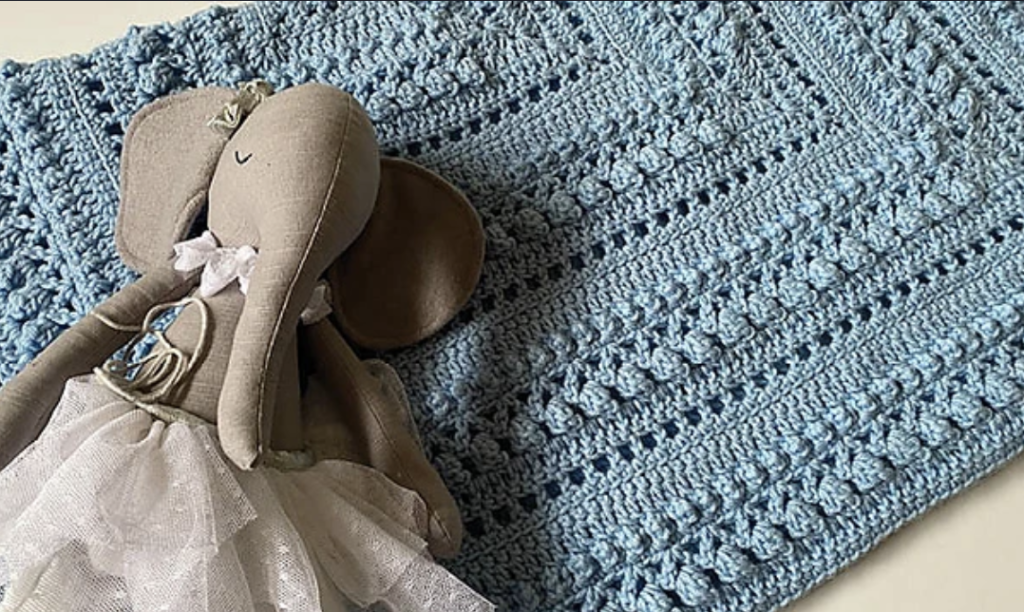 A stuffed elephant on the Baby Shower Crochet Blanket
